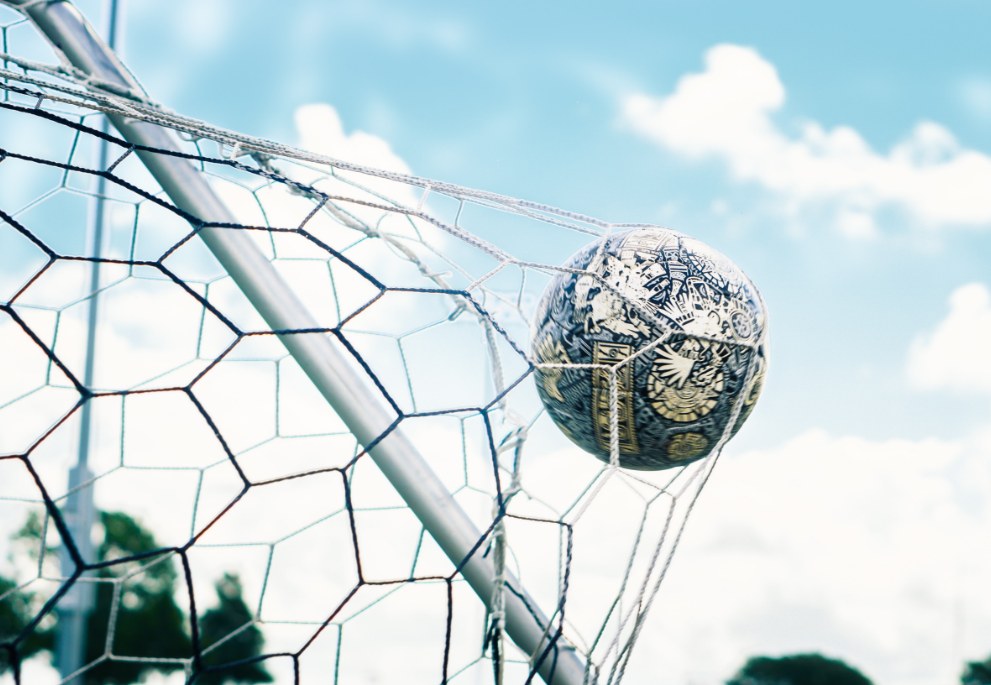 A close-up of a soccer ball that has just been kicked into the net.