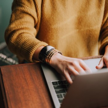 A man's hands typing on a laptop